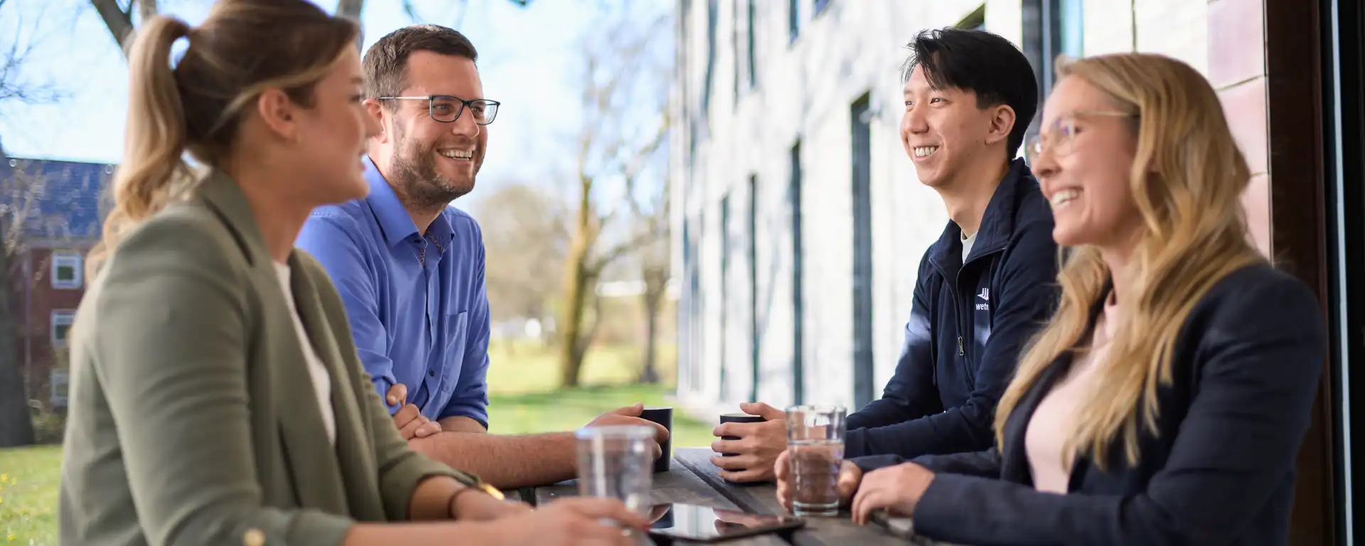 Eine Gruppe von Menschen sitzt im Freien an einem Holztisch